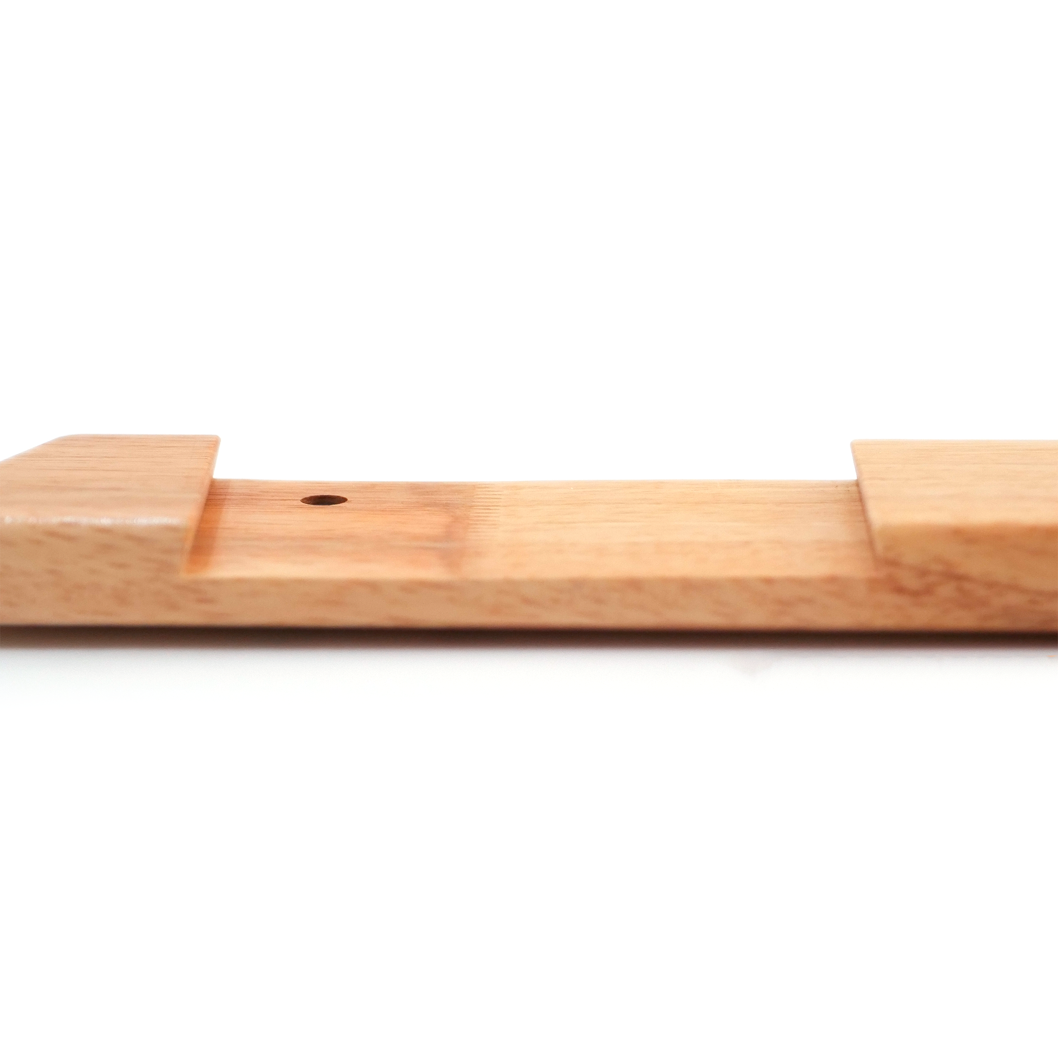 A close-up of a light natural wood block or tool with a small circular hole, shown against a plain white background.